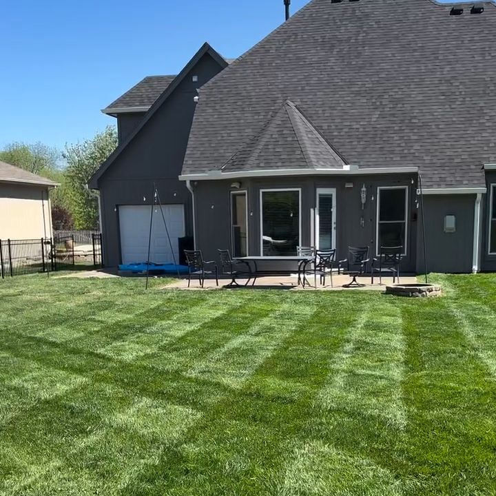 Striped back lawn behind a dark grey two-story house