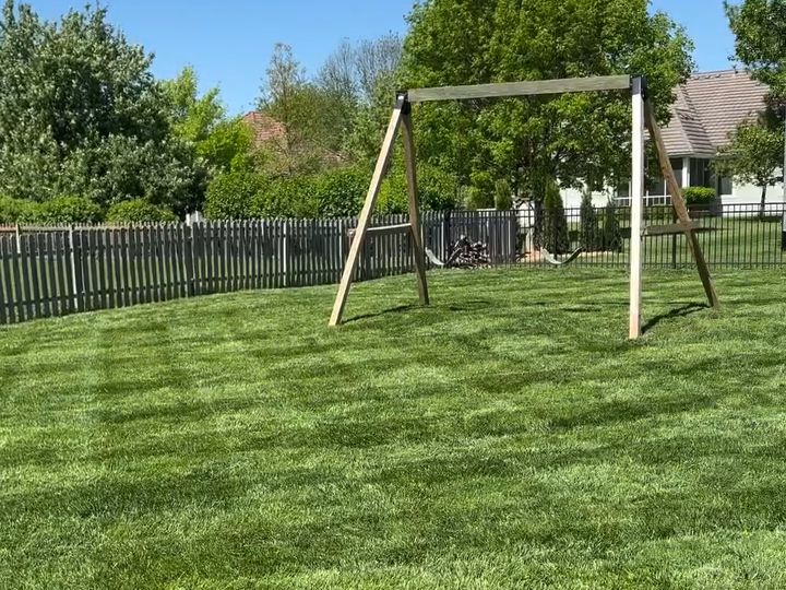 Large fenced back lawn with mowing stripes and a swing set